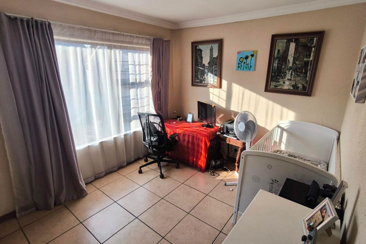 A functional bedroom featuring tiled flooring, cove cornicing, and a large window allowing for natural light.