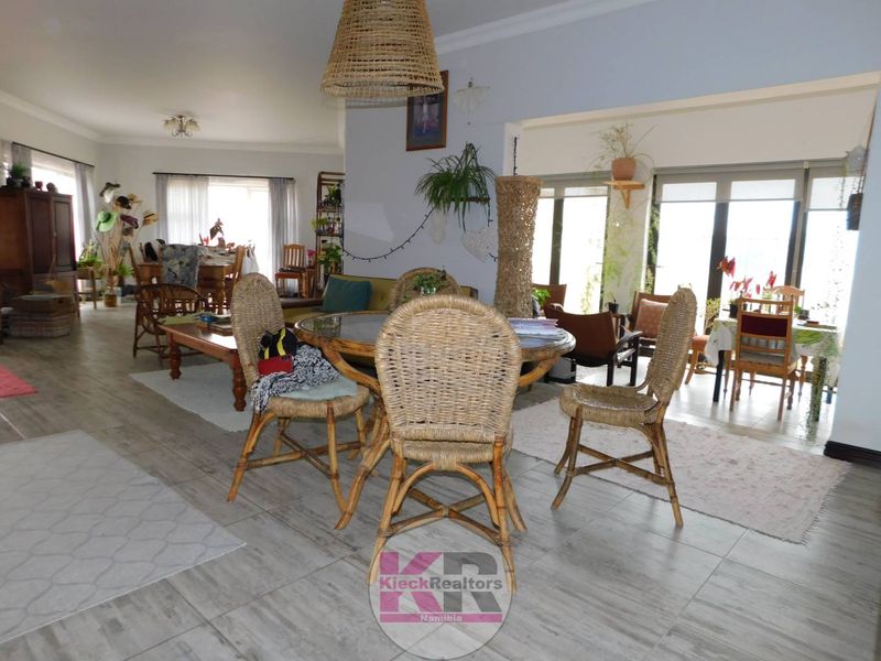 Spacious open-plan living and dining area featuring neutral tiled flooring and large sliding glass doors that provide ample natural light.