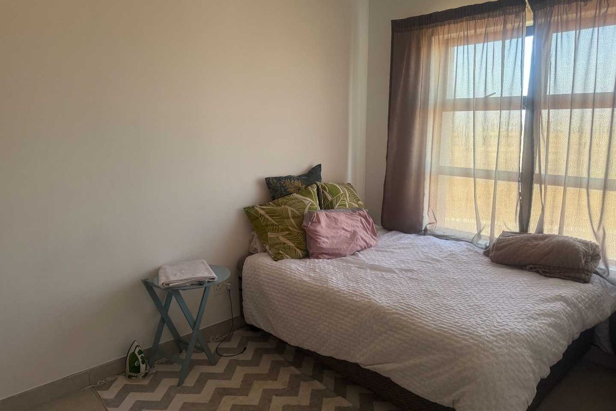 A bedroom featuring large windows with natural light, tiled flooring, and neutral wall finishes.