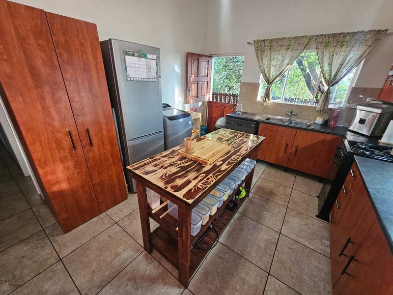 Functional kitchen featuring wood-finish cabinetry, tiled flooring, a central island, and direct access to the exterior.
