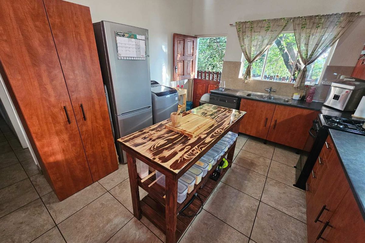 Functional kitchen featuring wood-finish cabinetry, tiled flooring, a central island, and direct access to the exterior.