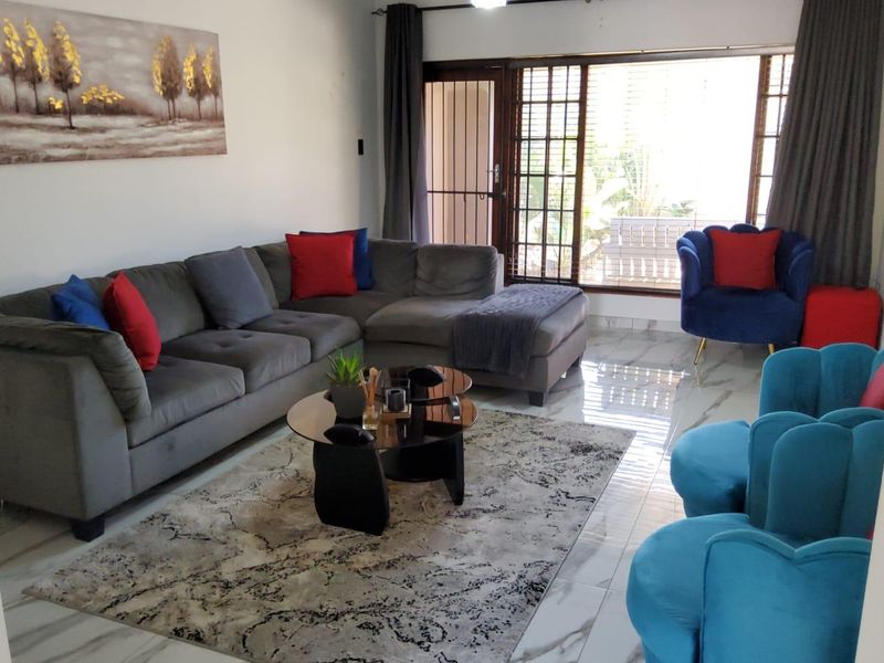 A bright living room featuring polished marble-look floor tiles and a large sliding glass door with an integrated security gate leading to the exterior.