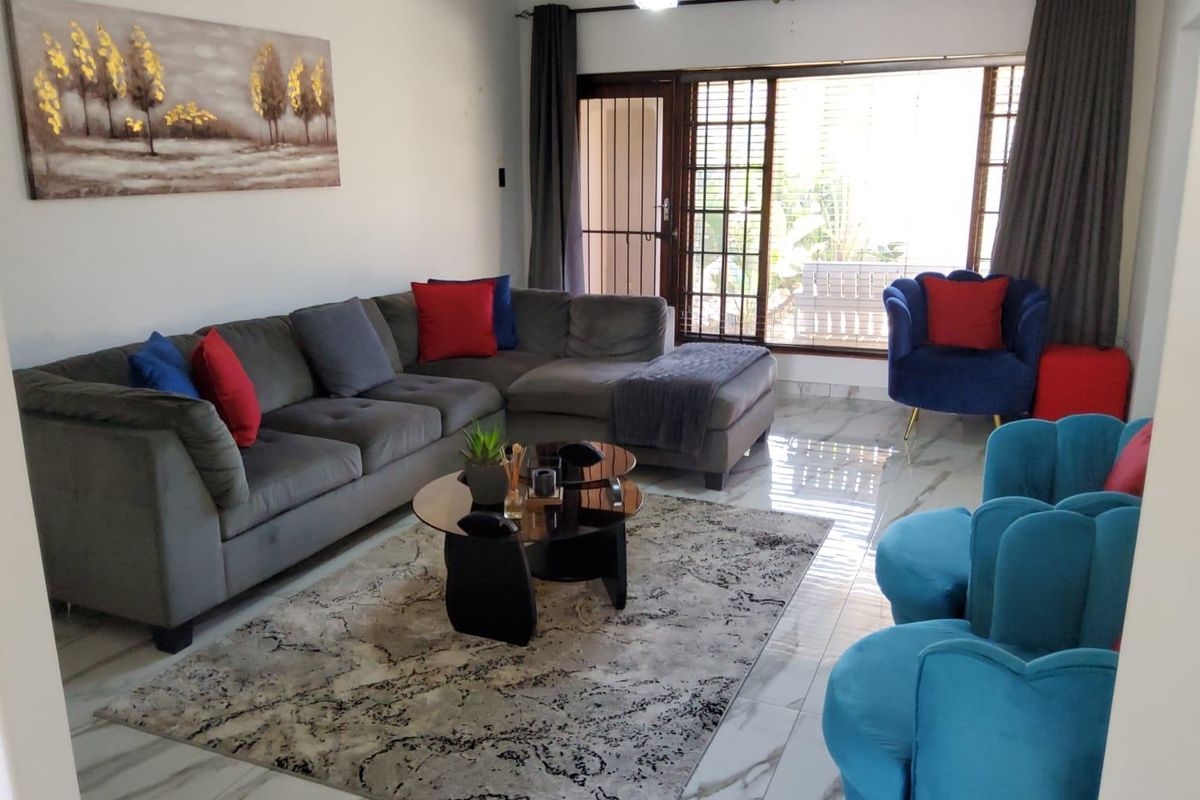 A bright living room featuring polished marble-look floor tiles and a large sliding glass door with an integrated security gate leading to the exterior.