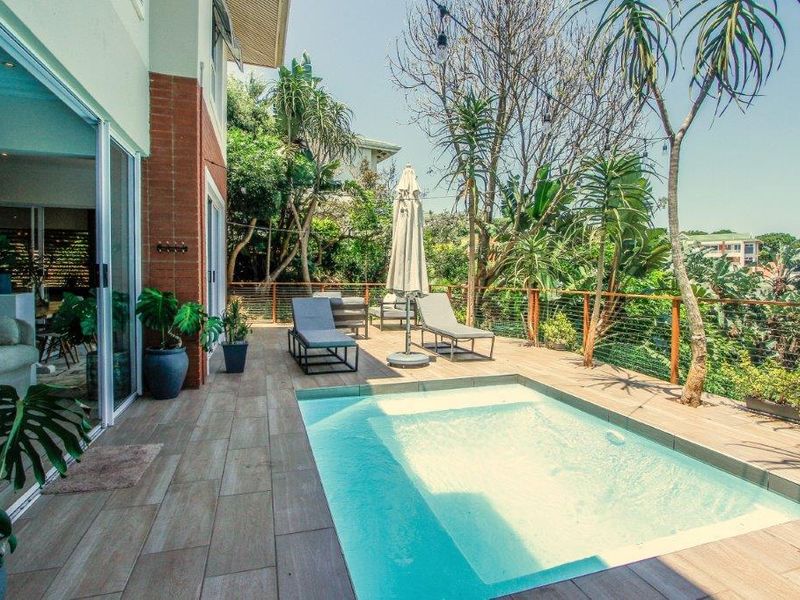 Outdoor pool area featuring timber decking, cable railing, and direct access to the interior through large sliding glass doors.
