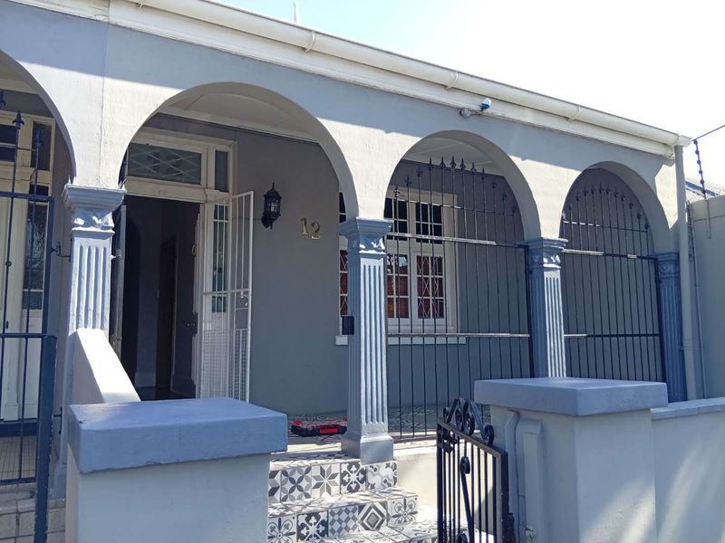 Charming front facade featuring an arched veranda with decorative tiling, fluted columns, and secure wrought iron gates.