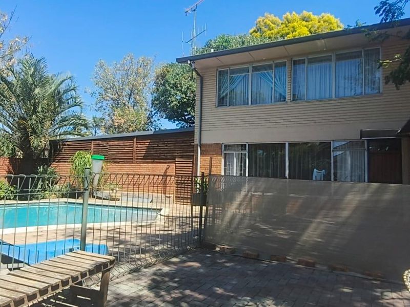 Rear exterior view featuring a swimming pool, paved patio area, and direct access to the home through sliding glass doors.