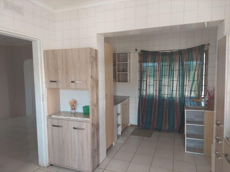 A functional kitchen space featuring tiled walls, built-in cabinetry, and tiled flooring, offering potential for modernization and aesthetic updates.