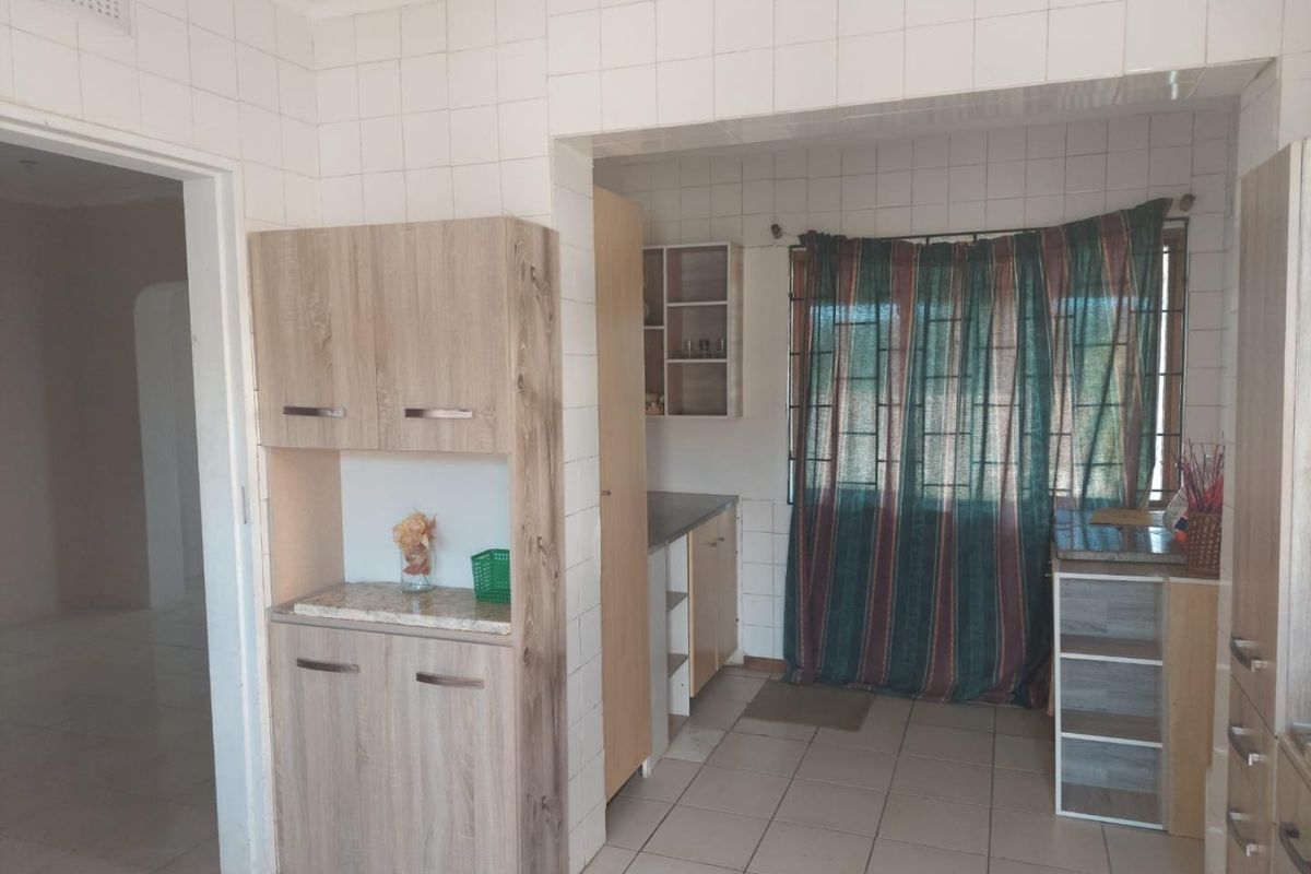 A functional kitchen space featuring tiled walls, built-in cabinetry, and tiled flooring, offering potential for modernization and aesthetic updates.