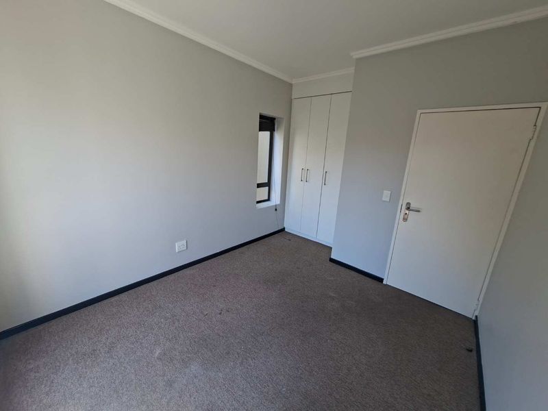 An empty bedroom featuring neutral walls, built-in cupboards, and carpeted flooring, providing a blank canvas for personalization.