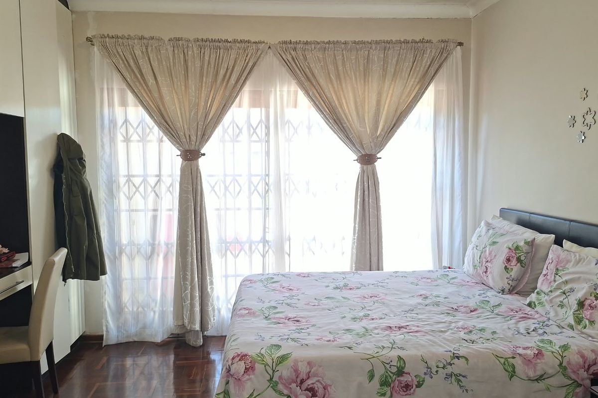 A bedroom featuring parquet flooring, a built-in wardrobe, and a sliding door with a security gate providing access to the exterior.