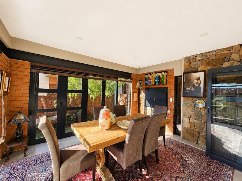 A characterful dining room featuring exposed brickwork, a natural stone feature wall, and black-framed folding doors that open to the garden.