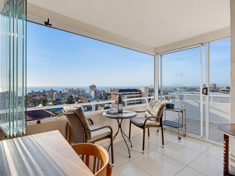 Enclosed balcony featuring glass stacker doors, tiled flooring, and expansive city and ocean views, providing a versatile indoor-outdoor living space.