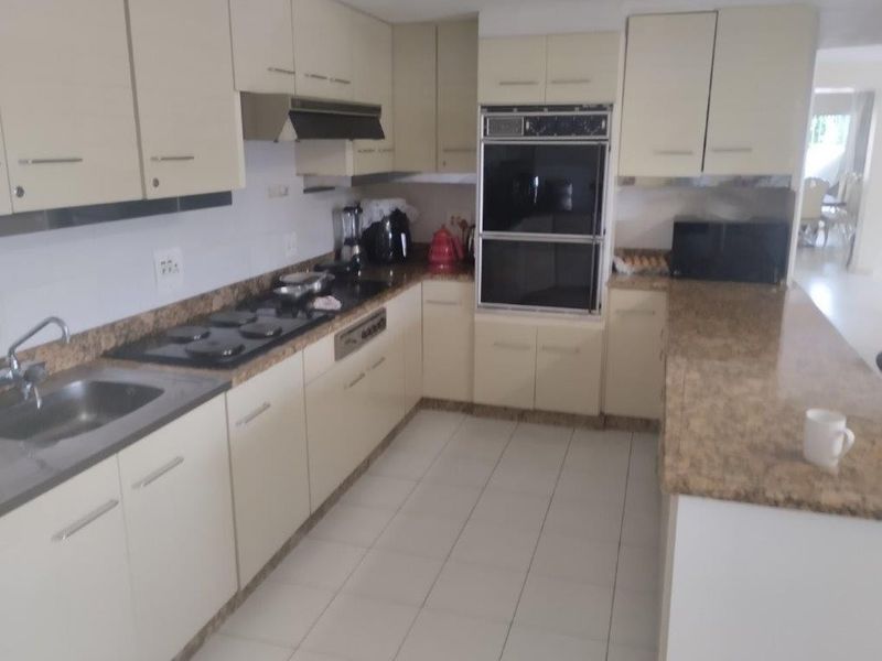 A functional kitchen featuring built-in cabinetry, laminate countertops, a double wall oven, and a cooktop with an integrated extractor fan.