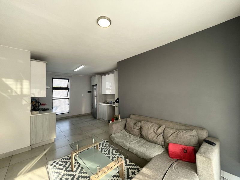 Open-plan living area featuring a modern kitchen with built-in cabinetry and tiled flooring, seamlessly connected to a comfortable lounge space.
