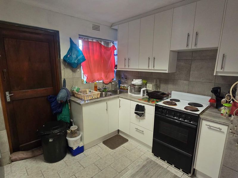 A functional kitchen featuring white cabinetry, tiled backsplash, and tiled flooring, providing a practical workspace with standard built-in fixtures.