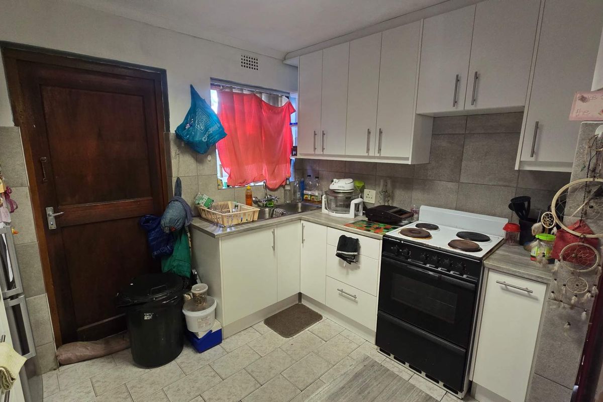 A functional kitchen featuring white cabinetry, tiled backsplash, and tiled flooring, providing a practical workspace with standard built-in fixtures.