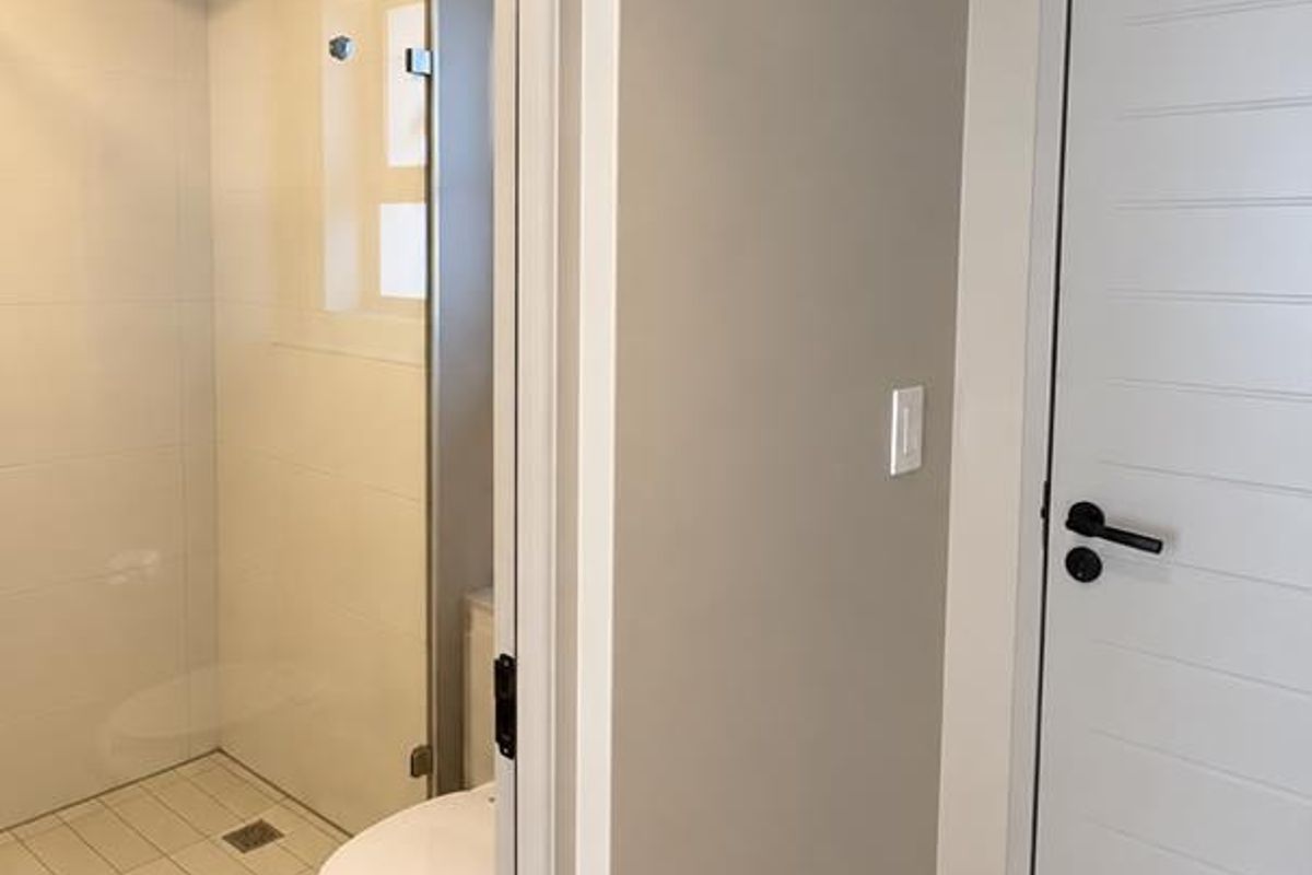A modern, clean bathroom featuring a walk-in shower with a rain shower head, glass screen, and neutral tiled flooring.