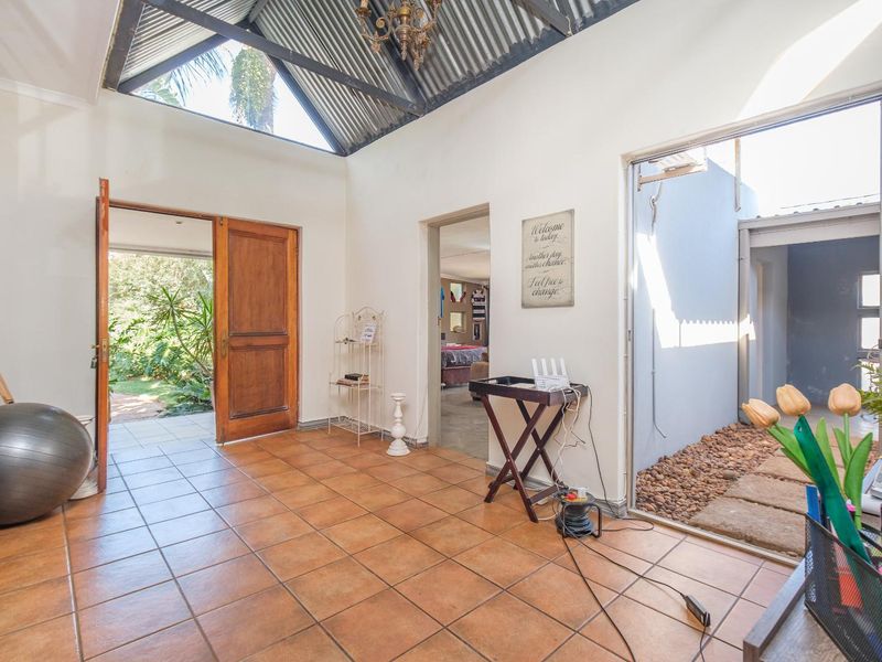 Spacious entrance hall featuring high vaulted ceilings with exposed trusses, ceramic tile flooring, and direct access to outdoor garden areas.