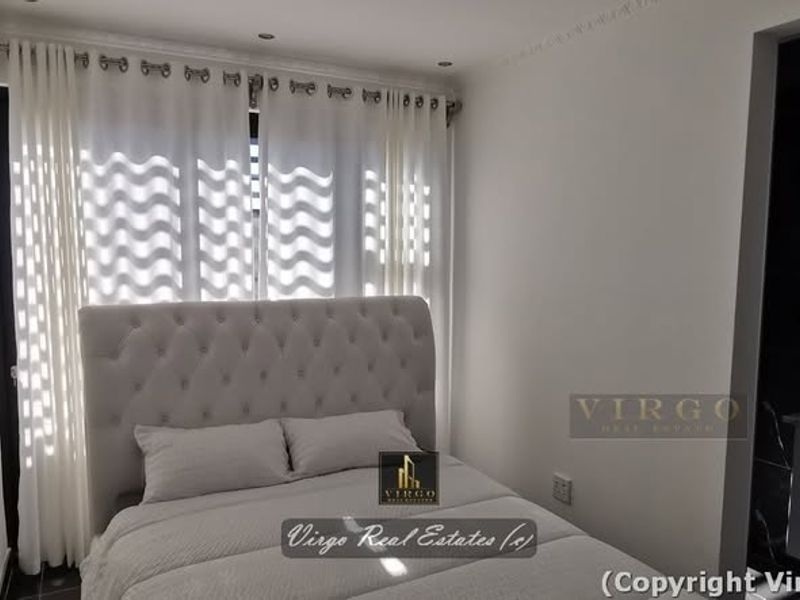 A modern bedroom featuring recessed downlights, decorative coving, and an integrated vanity area with a sleek finish.