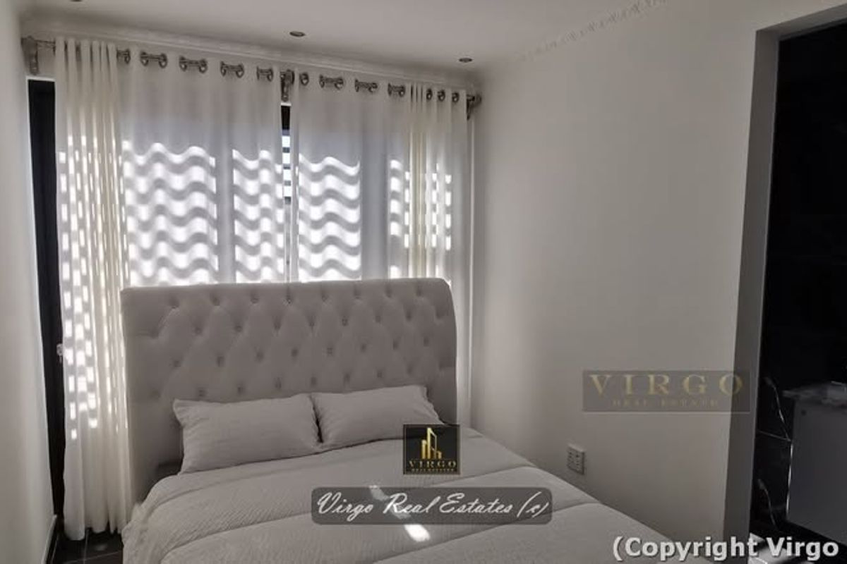 A modern bedroom featuring recessed downlights, decorative coving, and an integrated vanity area with a sleek finish.