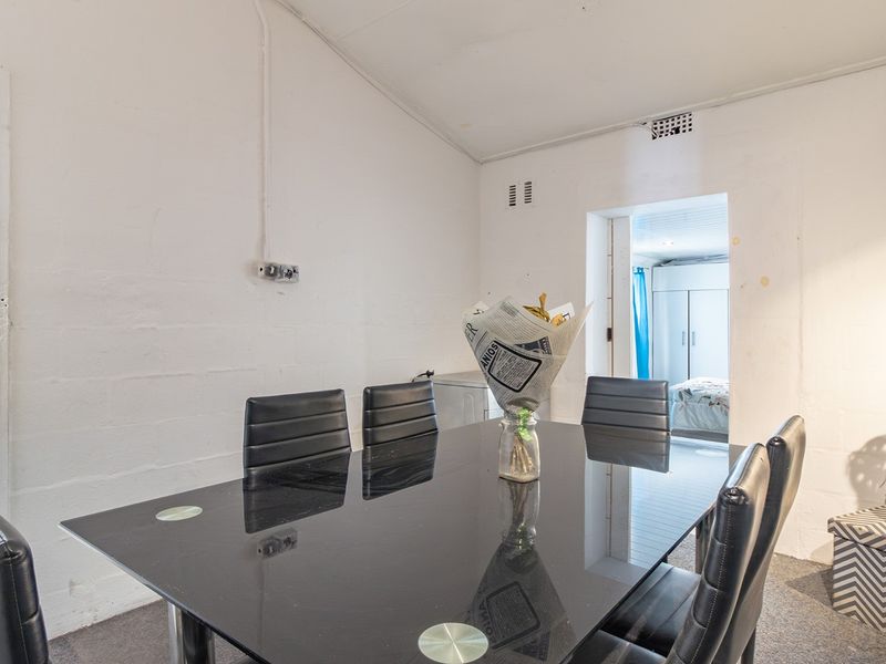 Dining area featuring exposed electrical conduit and ventilation grilles, providing a functional space with potential for cosmetic updates.