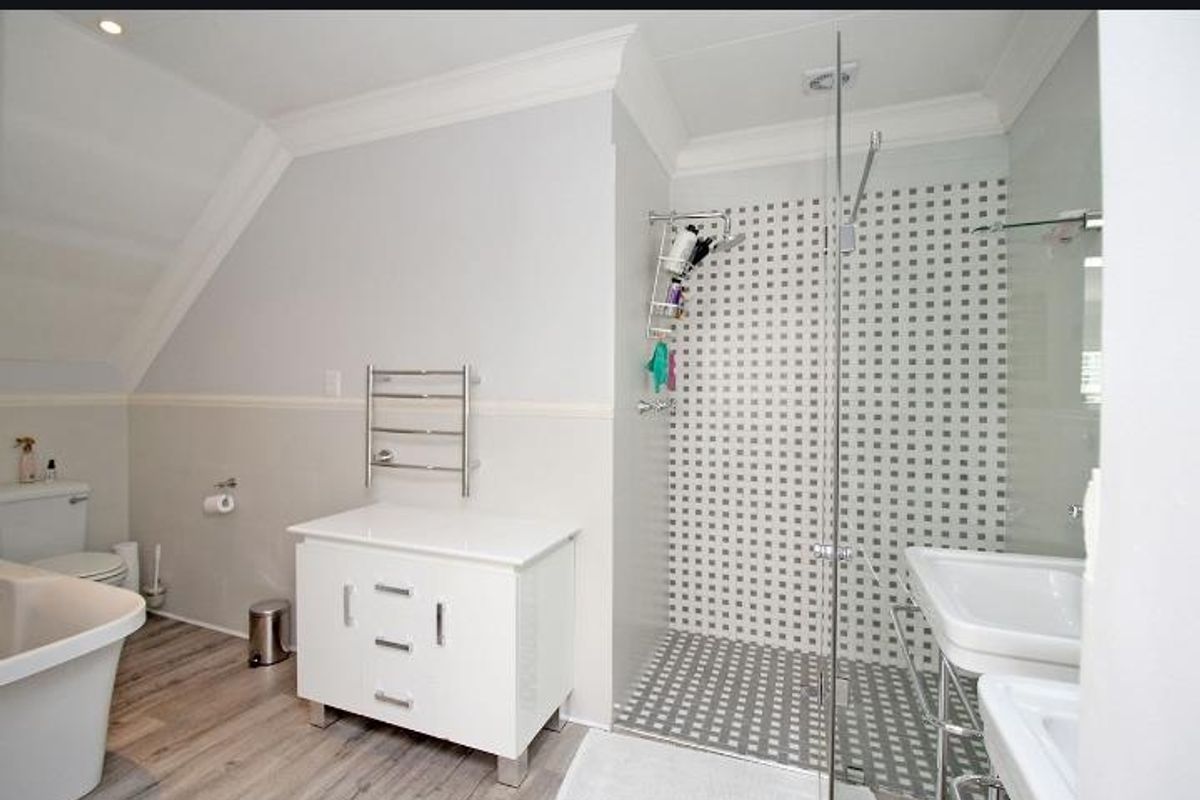 Modern bathroom featuring a walk-in shower with mosaic tiling, a freestanding bathtub, a vanity unit, and a heated towel rail.