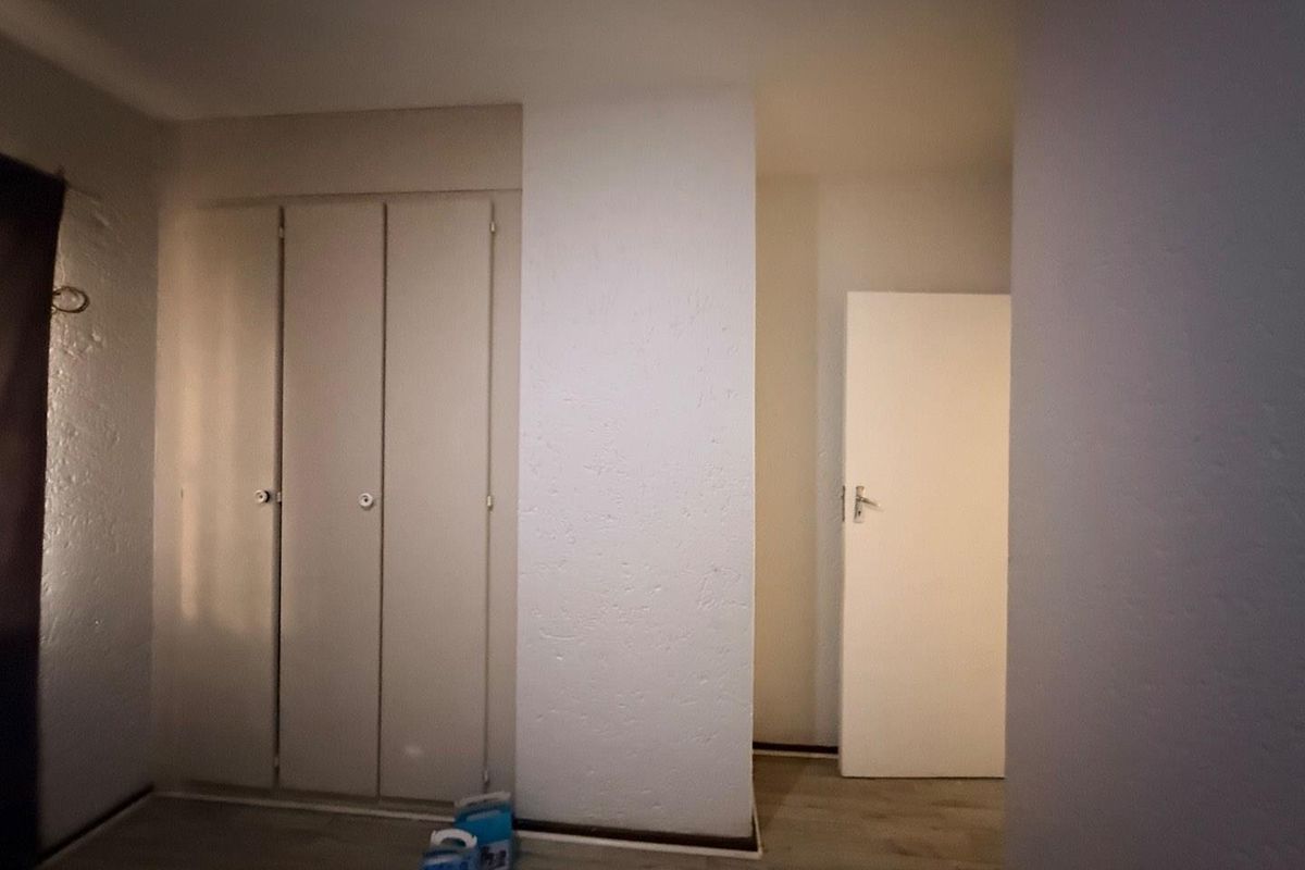 A simple bedroom featuring built-in wardrobes and laminate flooring, offering a neutral and functional space ready for personalization.