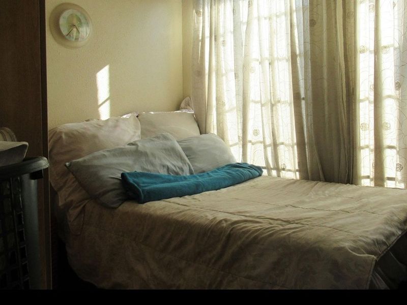A bedroom featuring natural light through glass-paned doors, providing a simple and functional sleeping space.