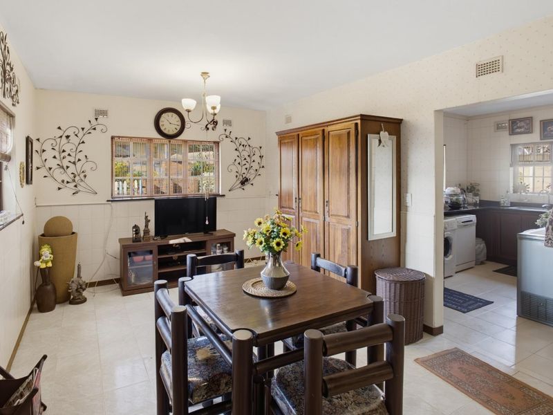 Open plan dining area featuring tiled flooring and half-wall tiling, with a seamless transition into the adjacent kitchen space.