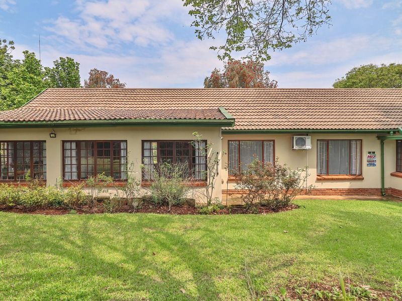 Rear view of a single-story house featuring a tiled roof, timber-framed windows, and a well-maintained lawn area.