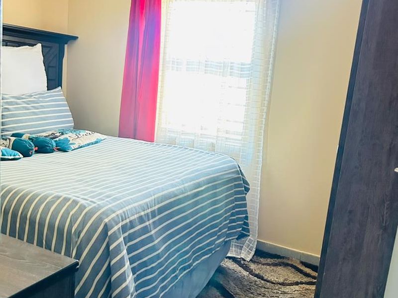 A standard bedroom featuring a window with natural light and a built-in wardrobe.
