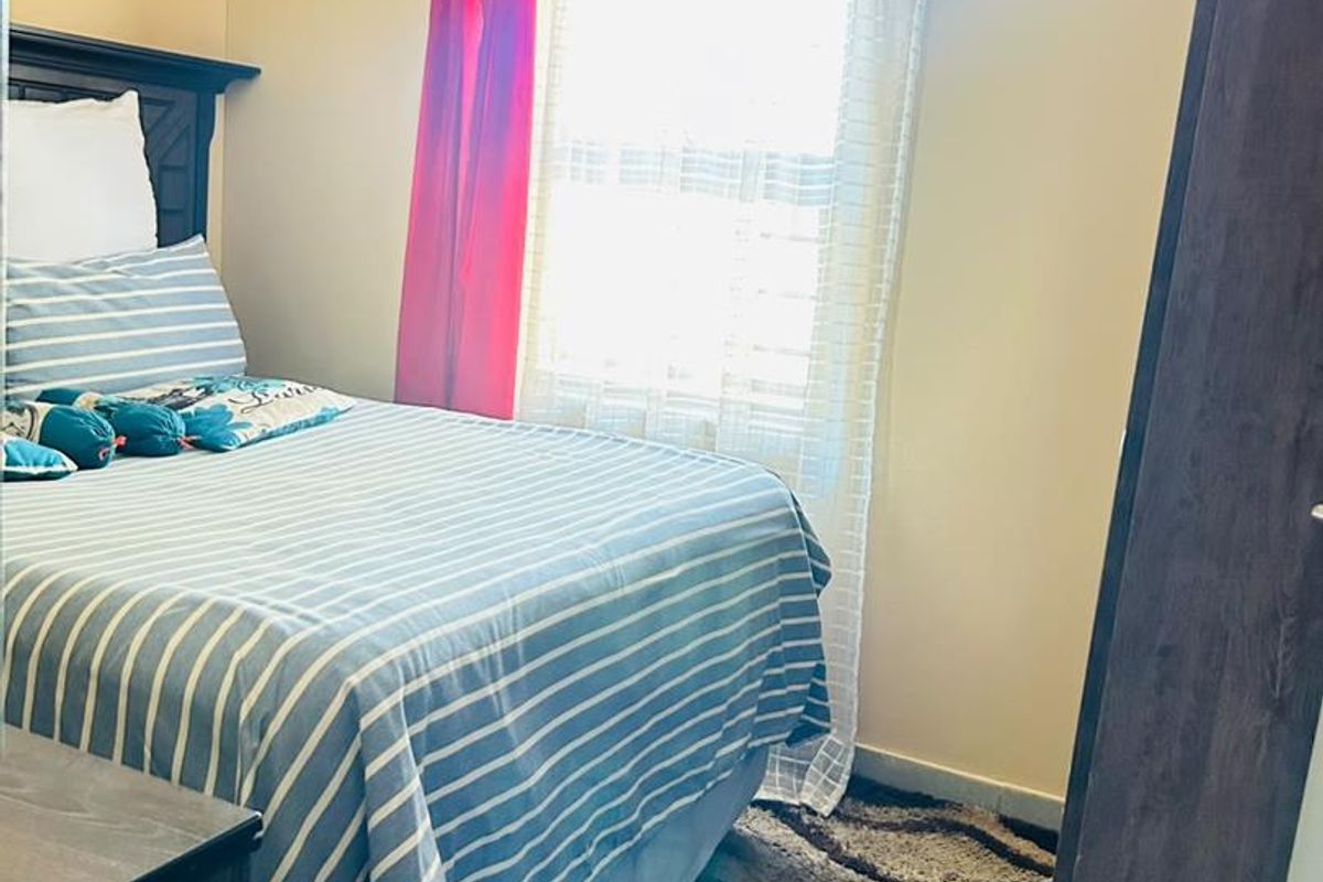 A standard bedroom featuring a window with natural light and a built-in wardrobe.