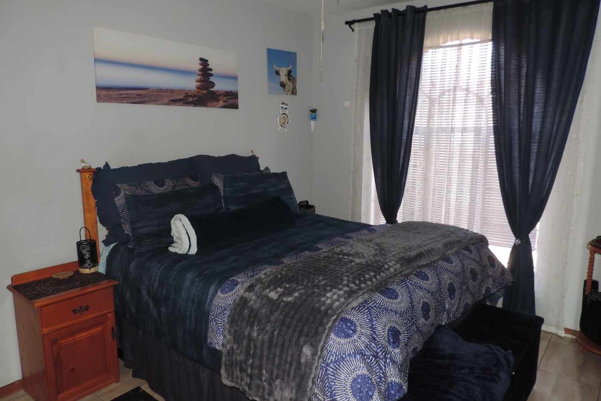 A bedroom featuring tiled flooring and a window with fitted curtain rods and blinds.