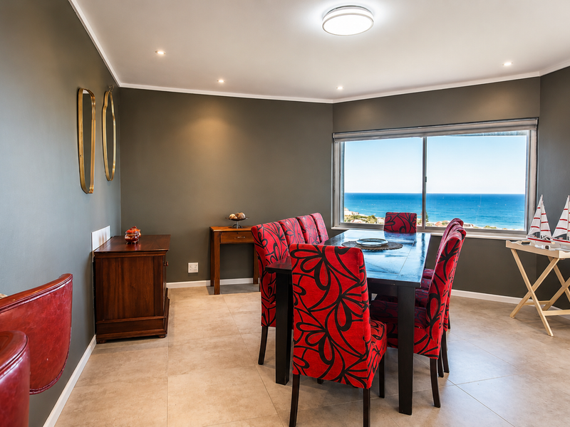 A well-lit dining room featuring tiled flooring, recessed lighting, and a large sliding window offering expansive ocean views.