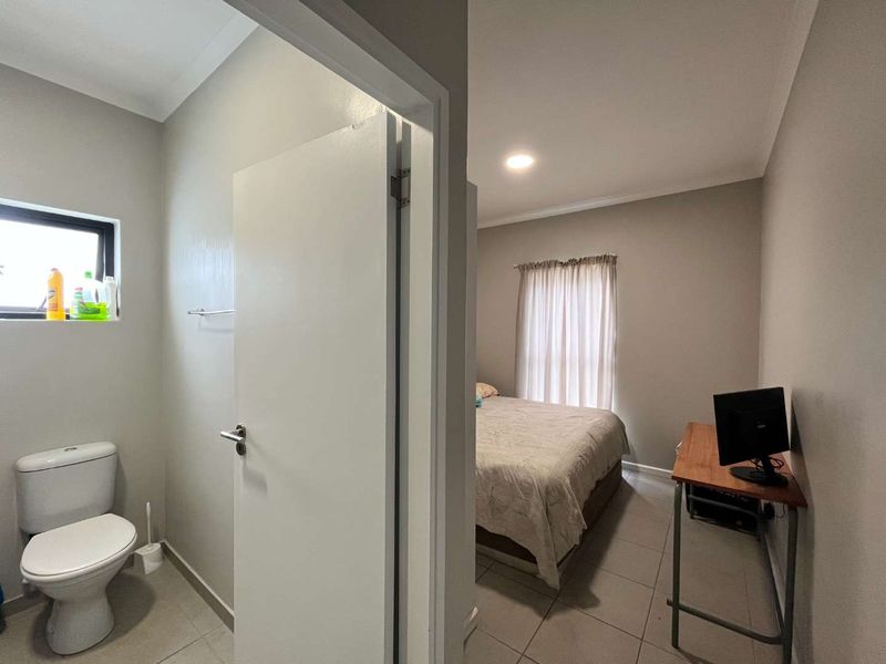 A view from a bathroom doorway looking into a bedroom featuring tiled flooring and neutral wall finishes.