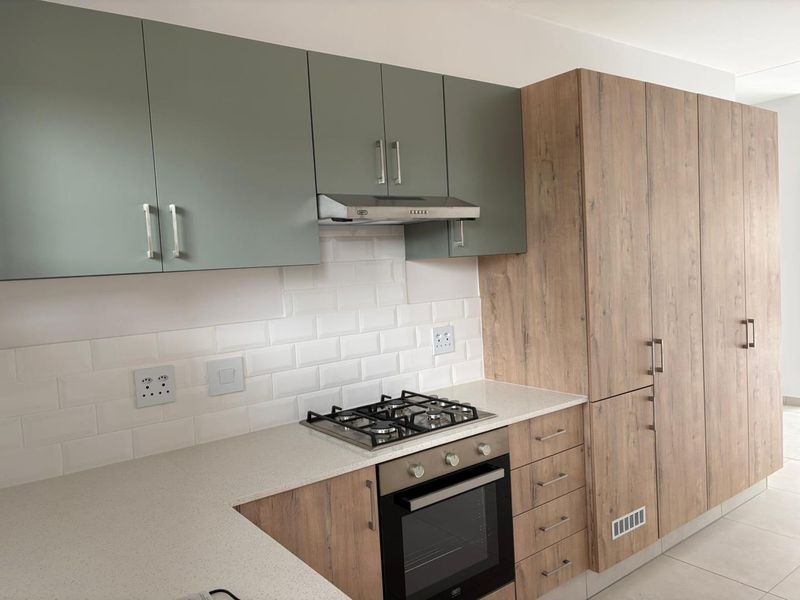 Modern kitchen featuring two-tone cabinetry, stone countertops, subway tile backsplash, and integrated stainless steel appliances including a gas hob and oven.