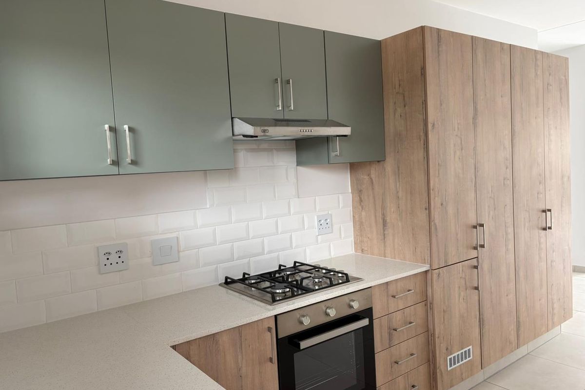 Modern kitchen featuring two-tone cabinetry, stone countertops, subway tile backsplash, and integrated stainless steel appliances including a gas hob and oven.