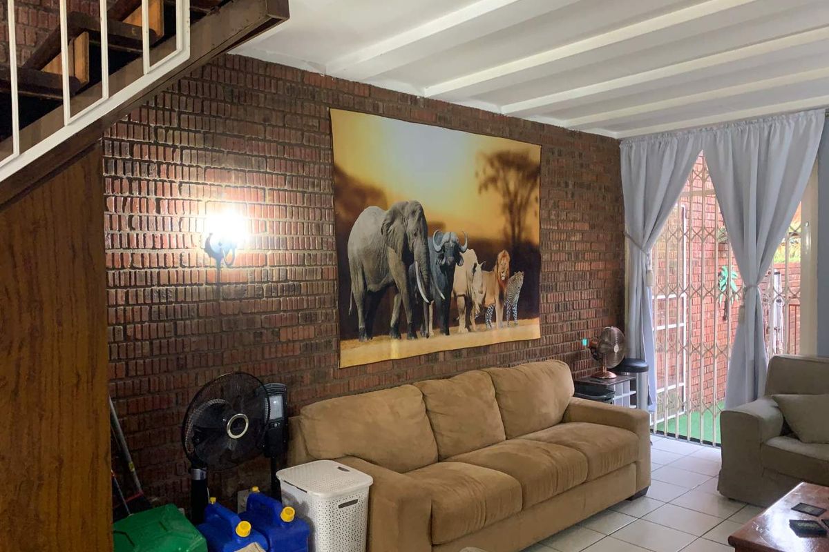 Living room featuring exposed brick walls, tiled flooring, and a staircase, with direct access to an outdoor area through a security gate.