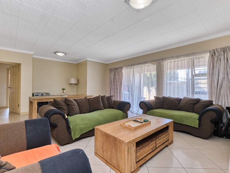 Spacious living room featuring tiled flooring, textured ceiling tiles, and large sliding glass doors providing access to the outdoor area.