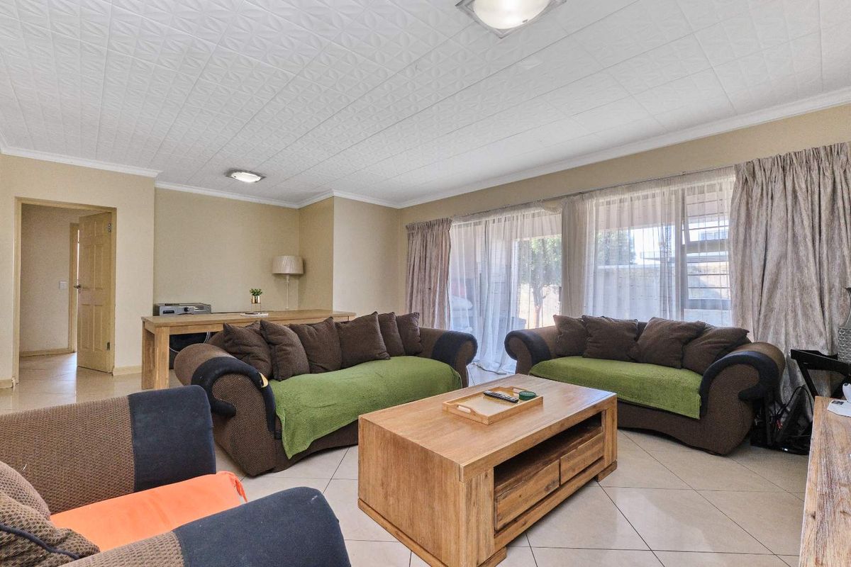 Spacious living room featuring tiled flooring, textured ceiling tiles, and large sliding glass doors providing access to the outdoor area.