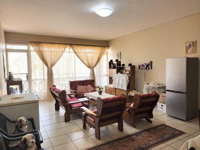 A spacious living area featuring tiled flooring and a large glass sliding door that provides ample natural light and access to the exterior.