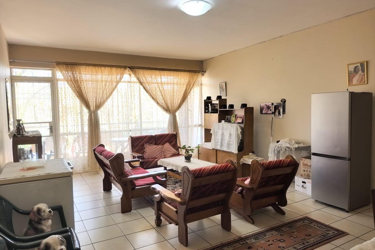 A spacious living area featuring tiled flooring and a large glass sliding door that provides ample natural light and access to the exterior.