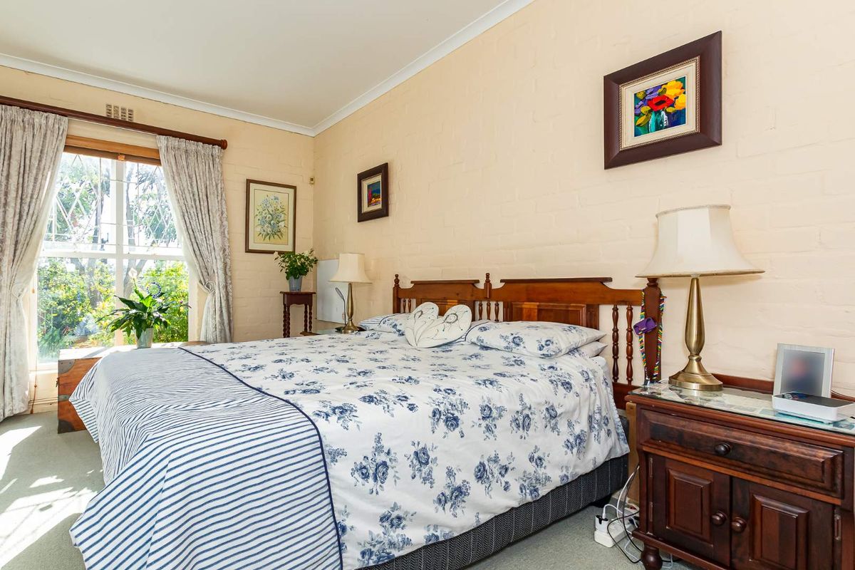 A bedroom featuring painted brick walls, carpeted flooring, and a large window allowing natural light.