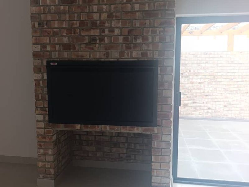 A bright living area featuring a prominent exposed brick fireplace with a built-in insert and a sliding glass door leading to an outdoor patio.