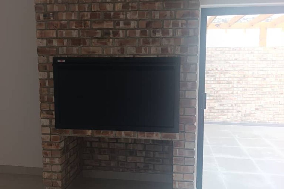 A bright living area featuring a prominent exposed brick fireplace with a built-in insert and a sliding glass door leading to an outdoor patio.