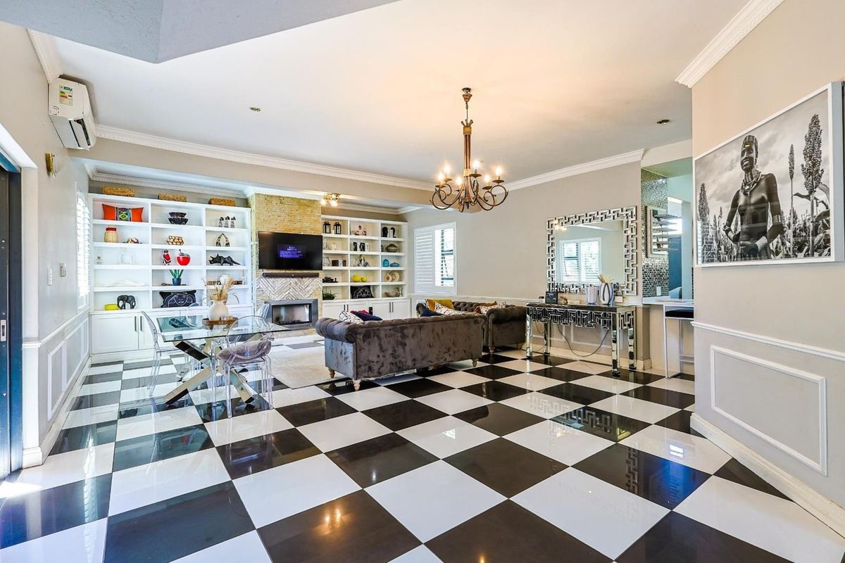 Spacious living room featuring a fireplace with stone surround, built-in shelving, crown molding, and distinctive black and white checkered tile flooring.