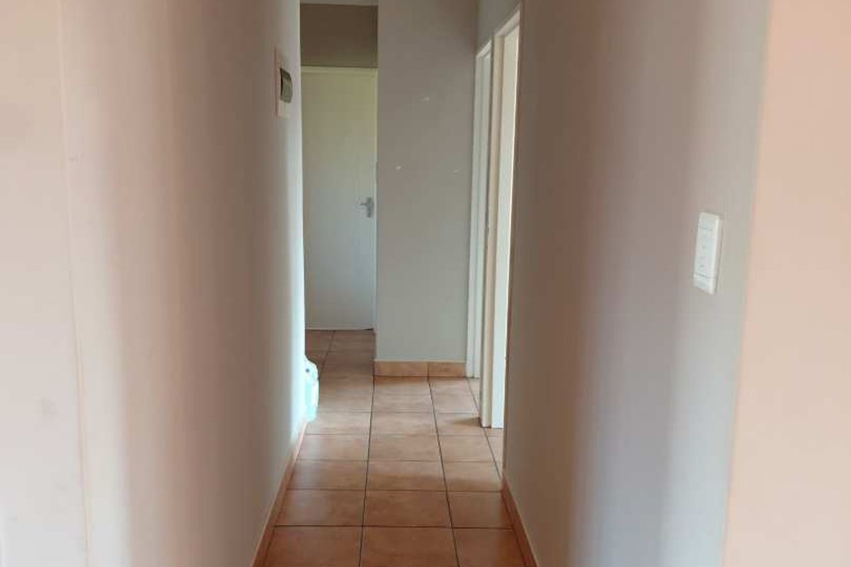A functional interior hallway featuring neutral wall tones and durable ceramic floor tiles, providing access to multiple rooms within the townhouse.