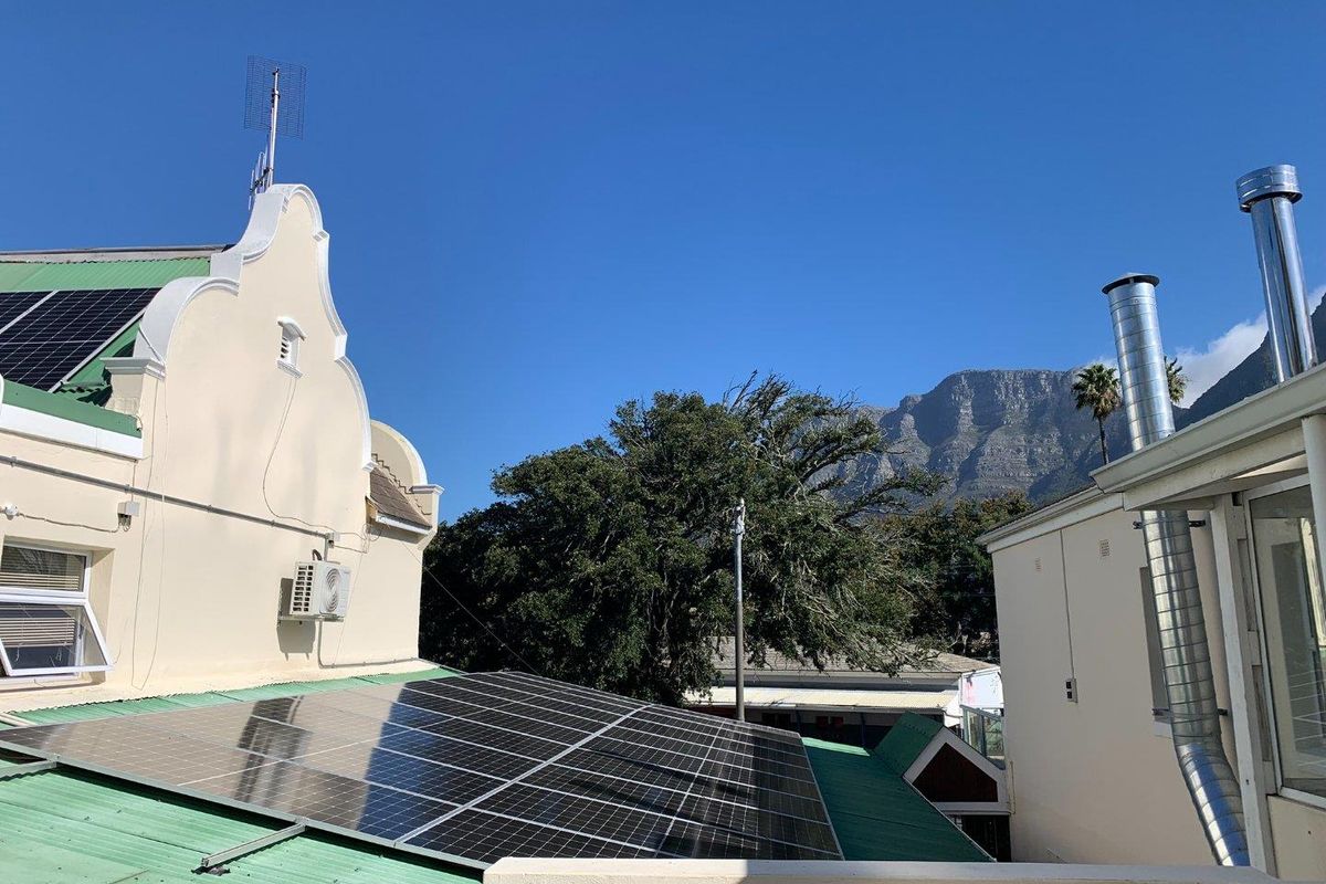 Exterior view of the property roof featuring installed solar panels, metal chimney flues, and a clear view of the mountain backdrop.