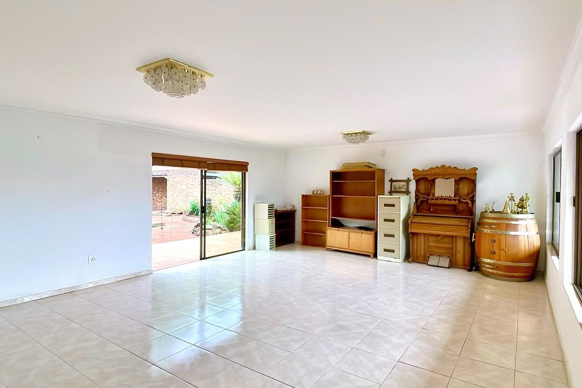 Spacious living area featuring neutral tiled flooring, large sliding glass doors providing natural light, and access to an outdoor patio space.