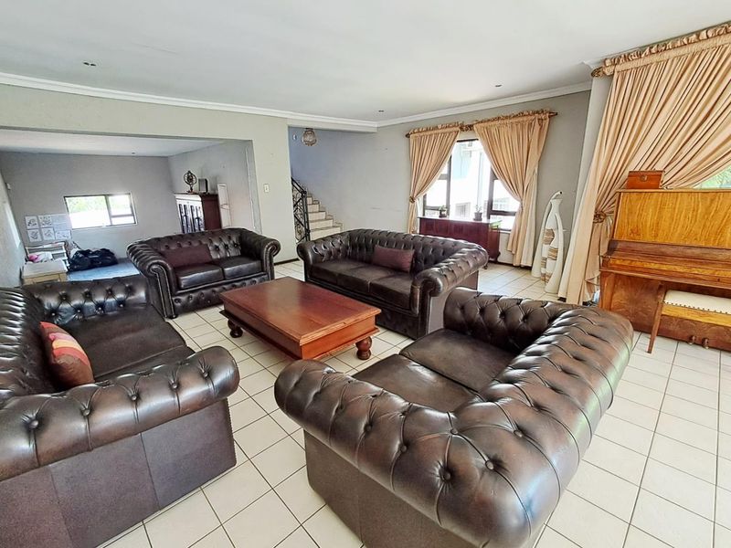 Spacious living room featuring tiled flooring, coved ceilings, and an open-plan layout leading to a staircase area.